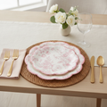 Pink floral scalloped disposable paper dessert plates styled on a woven placemat with gold flatware and white roses