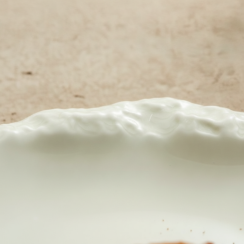 Macro of the crumpled kiln-turned pinched rim and glossy white glaze of the Crosta plate