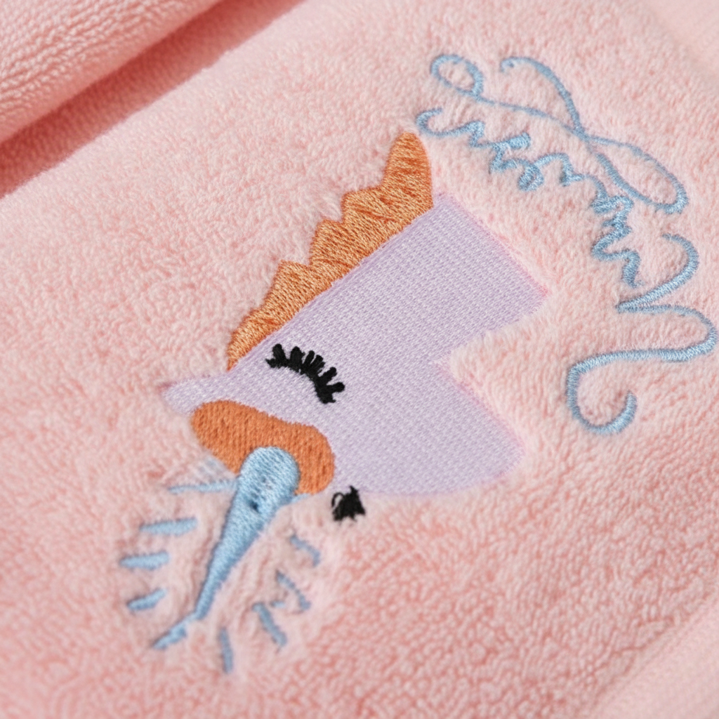 Close-up of embroidered unicorn on plush pink cotton terry towel