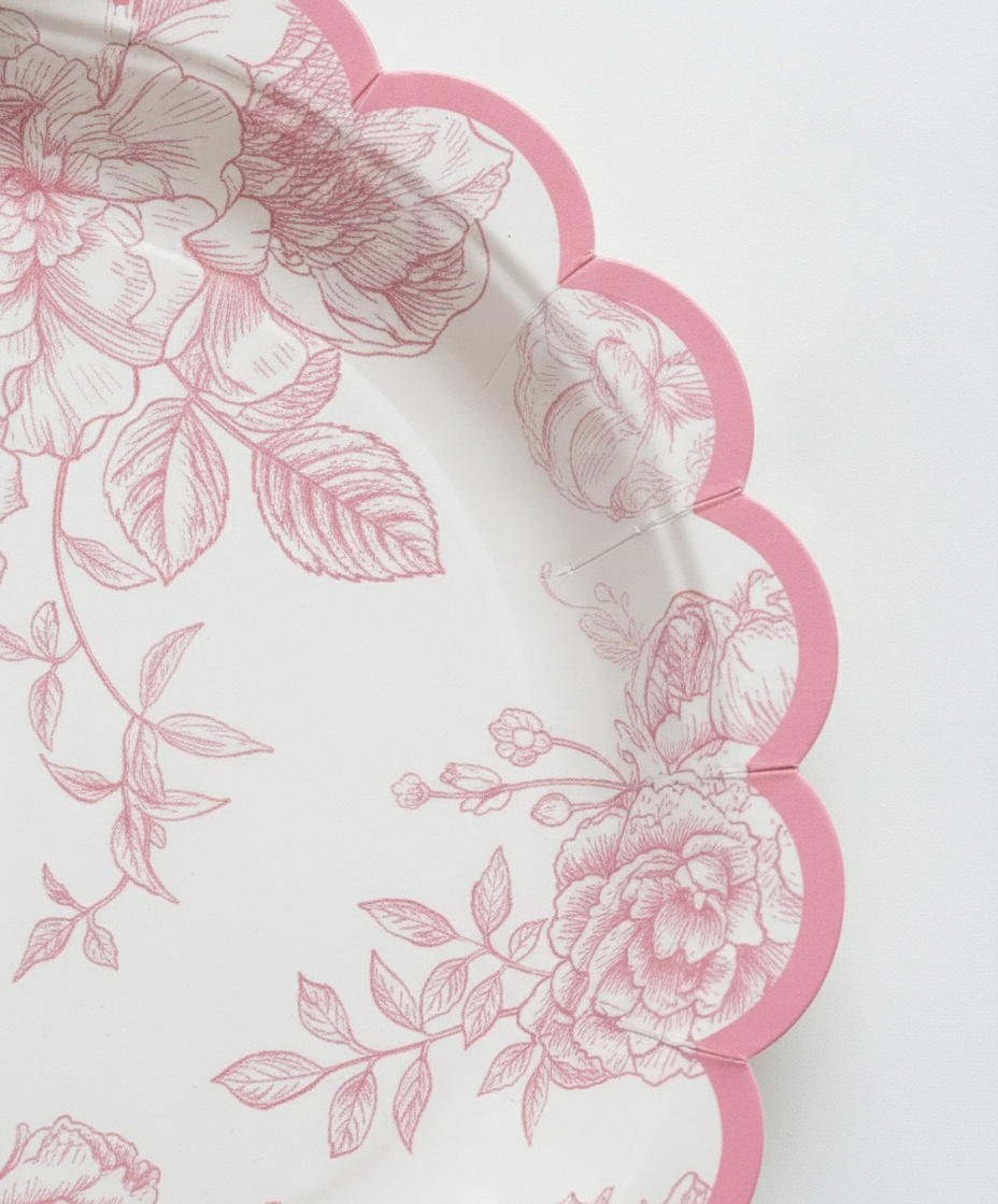Macro close-up of pink toile floral disposable paper plate scalloped rim showing matte paper texture
