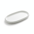 Ovale matte-white oval porcelain serving platter with rough stone-textured rim on white