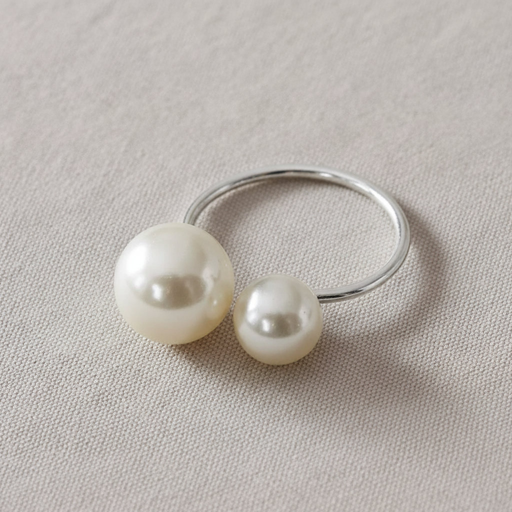 Close-up of a silver wire napkin ring with one large and one small white pearl
