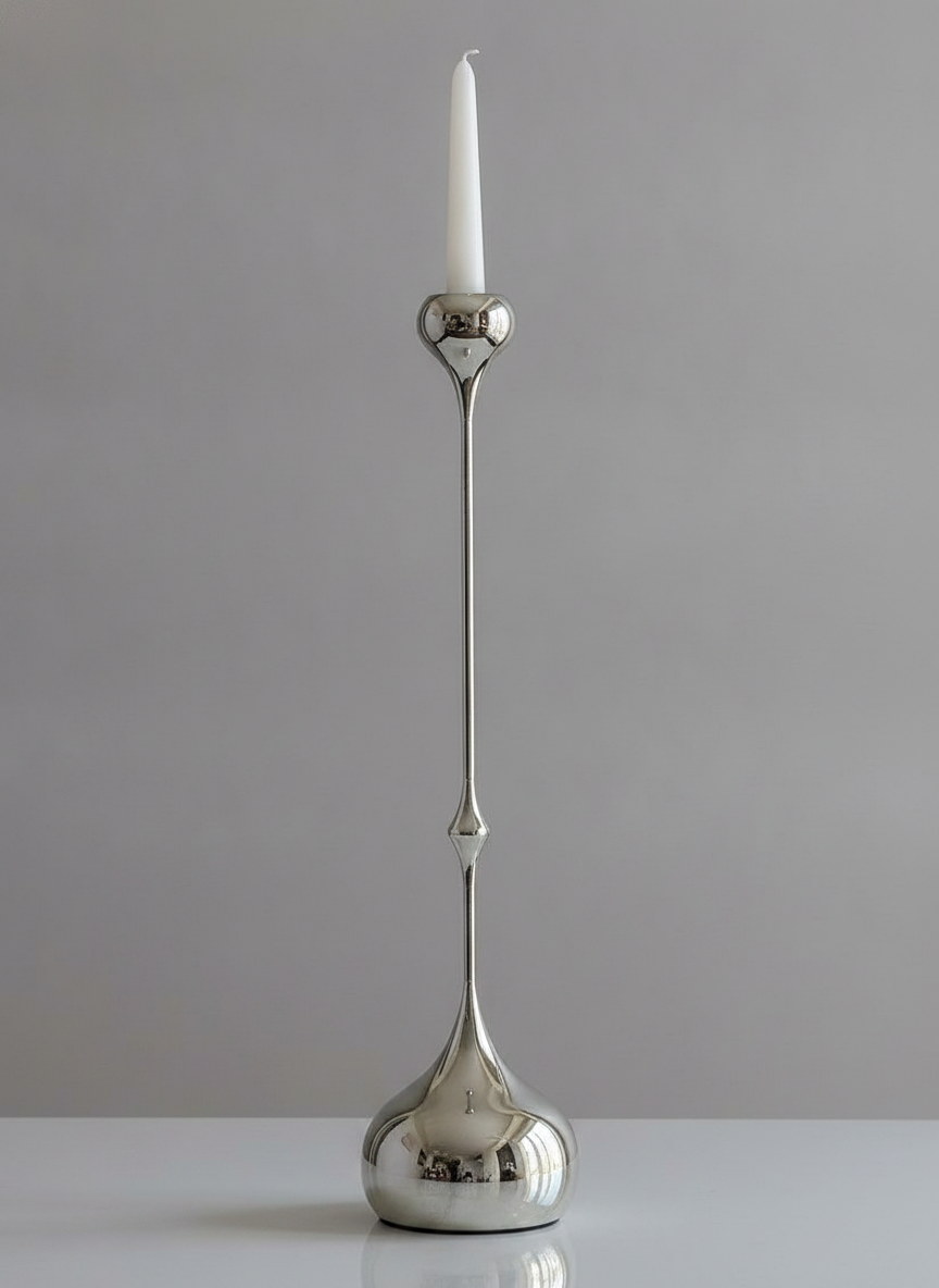 Single tall Goccia teardrop candlestick with a lit taper, dramatic side lighting on a grey backdrop
