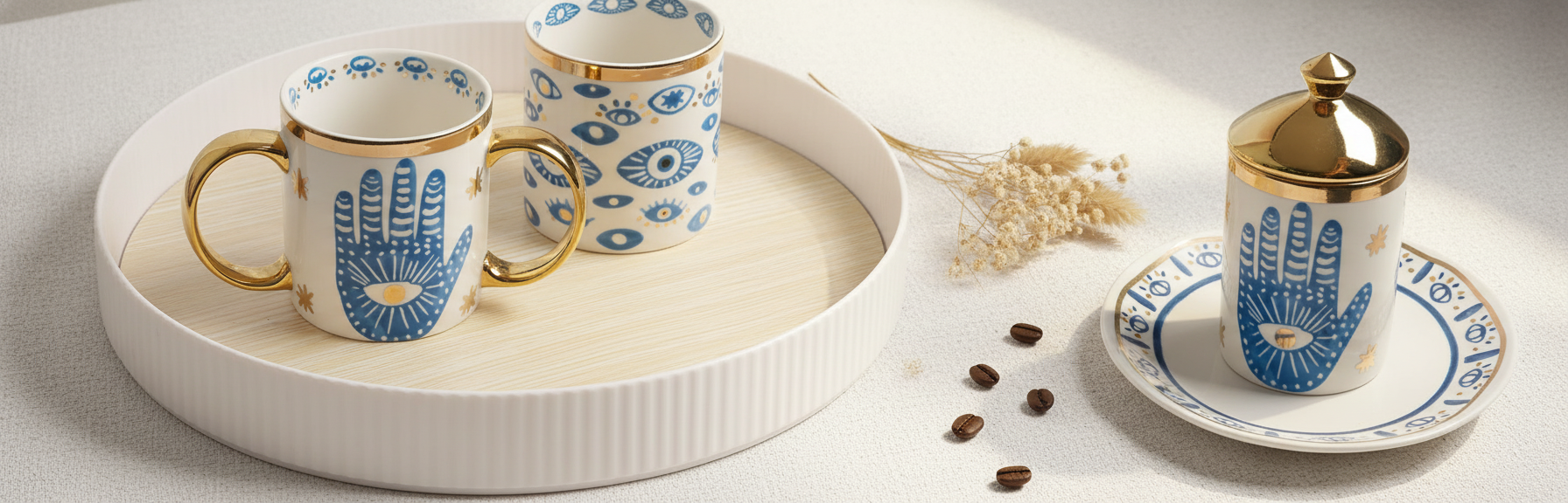 Blue hamsa hand and evil-eye porcelain mugs with gold handles and gold-lidded jar on a tray