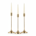 Nozze set of three graduated gold taper candlestick holders with ivory candles on white