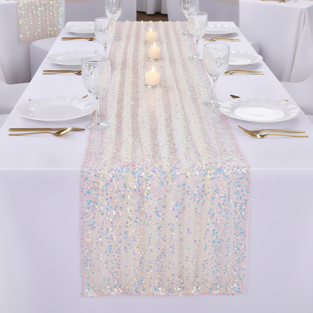 Champagne sequin runner down the center of an elegant wedding table with white plates, gold cutlery and candlelight