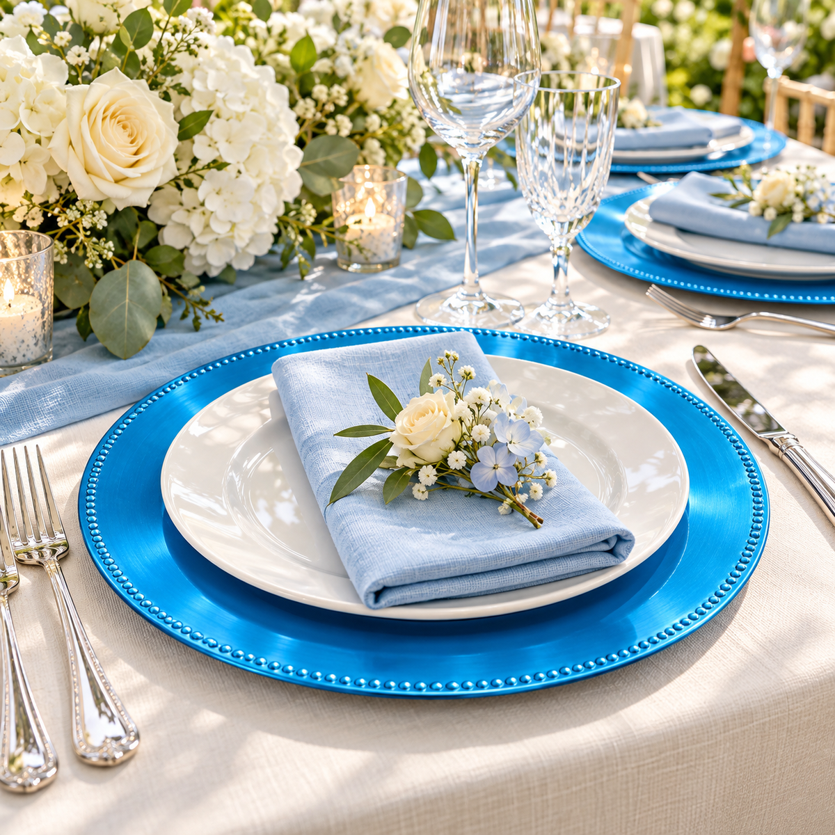 Bright blue beaded charger beneath a separate white dinner plate at a floral garden wedding setting. Representative arrangement; food and styling props not included.