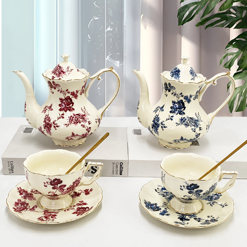 Retro gold-trim ceramic tea cups and saucers with French-style teapot on marble surface