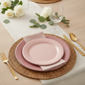 Dusty pink gradient disposable paper plates and napkins styled on a woven placemat with gold flatware and eucalyptus