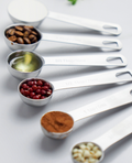 Stainless steel measuring spoons holding ingredients in several sizes.