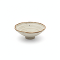 Cream speckled stoneware petal-rim bowl with amber edge on a white background