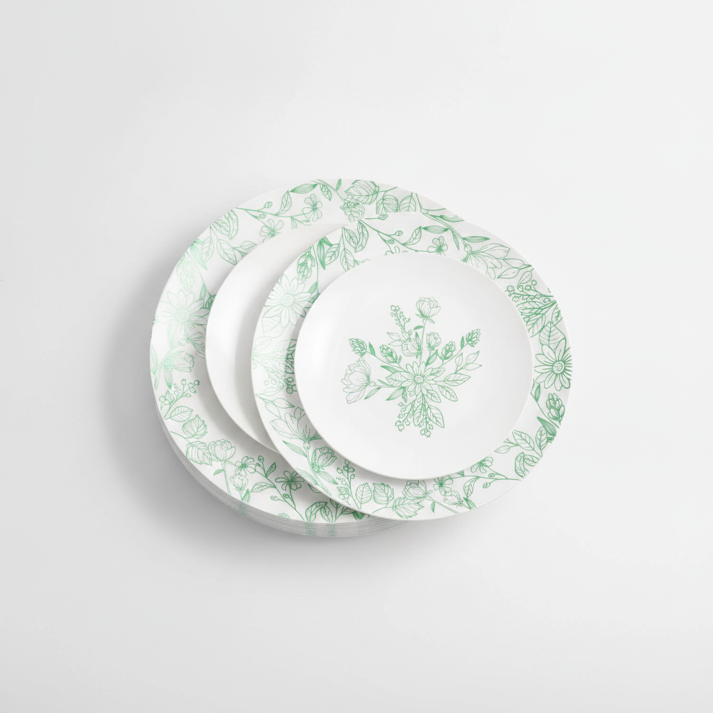 White and green floral disposable plastic plates fanned in a stack on a white background