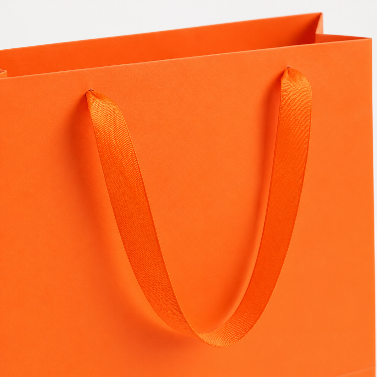 Close-up of orange gift bag ribbon handle and paper rim