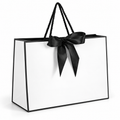 White gift bag with black border, cord handles and satin bow on white background