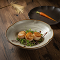 Petal-rim stoneware bowl plated with seared scallops in a fine-dining setting