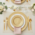 Gold chain-pattern charger plates in a modern luxe wedding place setting with gold cutlery, blush napkin, glassware and white roses