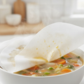 Close-up of white non-woven oil-control filter sheet lifted off broth with absorbed oil