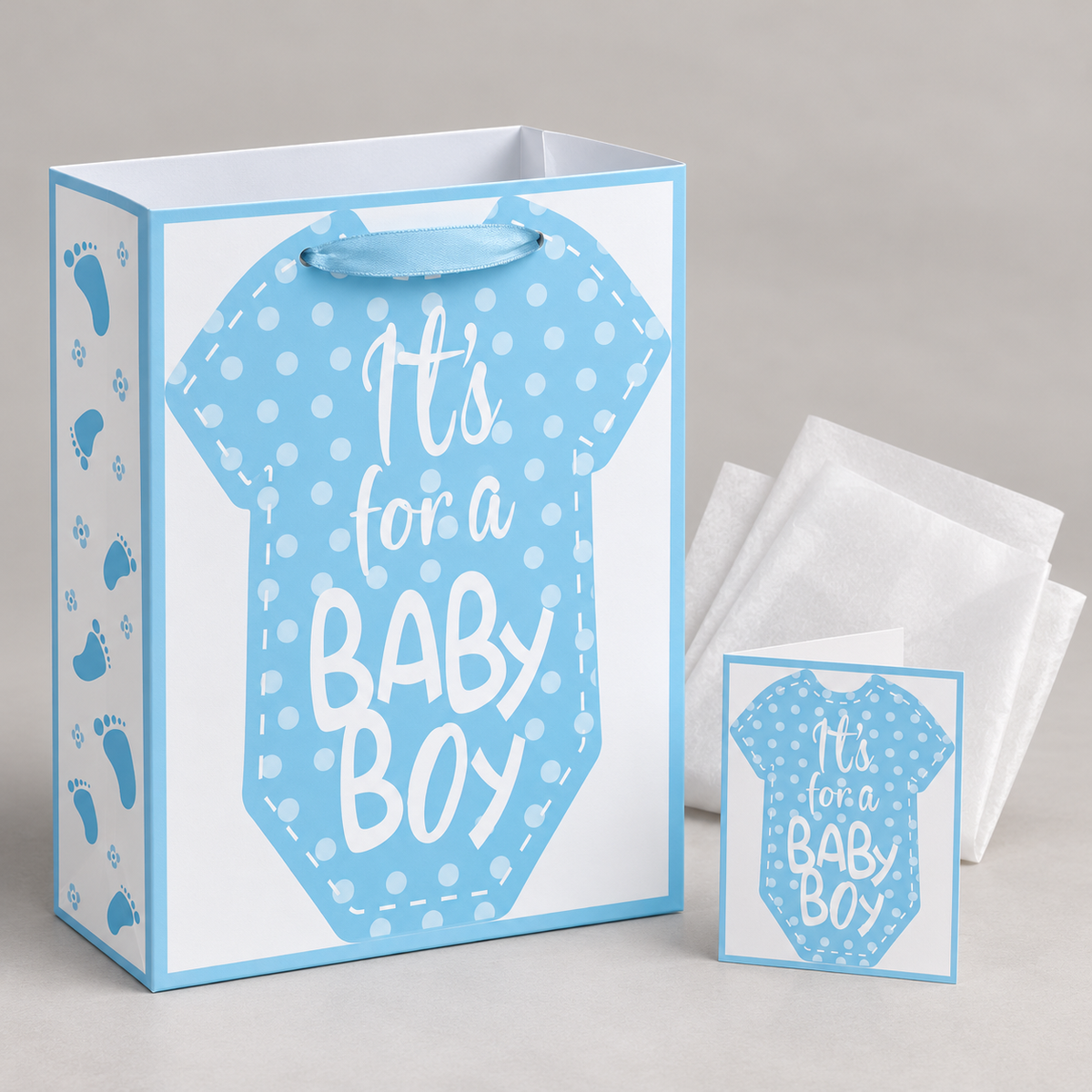 Blue paper gift bag showing satin ribbon handle and matching card with white tissue paper