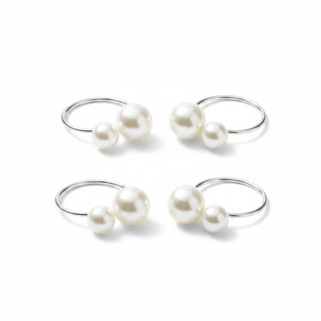 Set of silver pearl napkin rings, each with two white pearls, on a white background