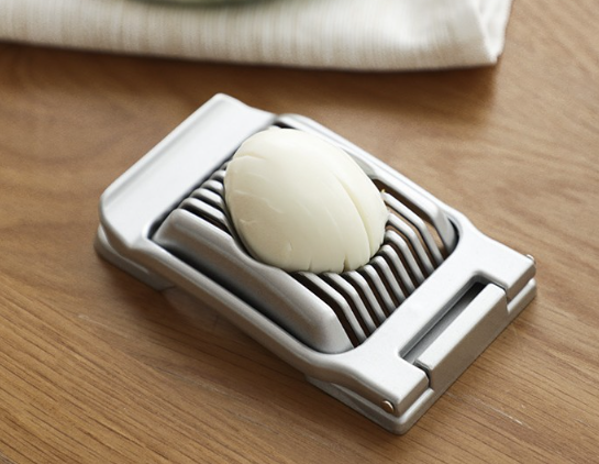 Silver aluminum egg slicer with sliced egg