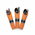 Pre-rolled black plastic cutlery wrapped in burnt orange napkins fanned on white