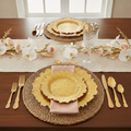 Gold ruffled reef-rim charger plates in an opulent banquet place setting with gold cutlery, blush napkin, woven placemat and orchid florals