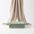 Soft folded cotton gauze towel in sage green on white background
