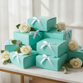 Stack of glossy turquoise teal gift boxes with white satin bows on marble