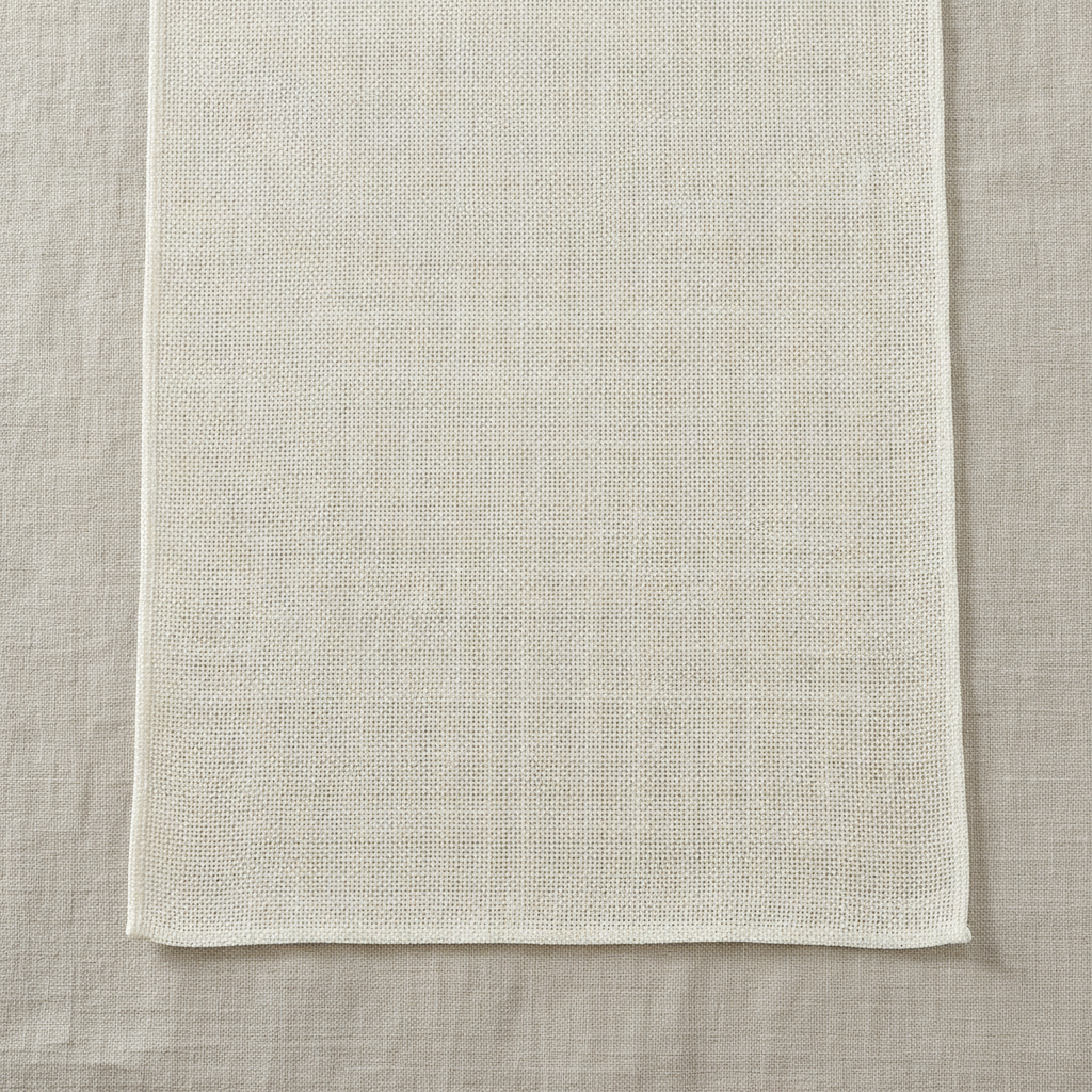 Flat-lay detail of the hemmed end of the cream burlap table runner