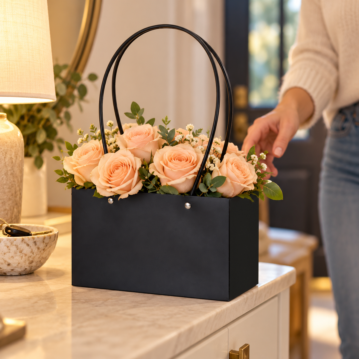 Black floral tote with peach roses on a home entry console. Flowers and decor are styling props.