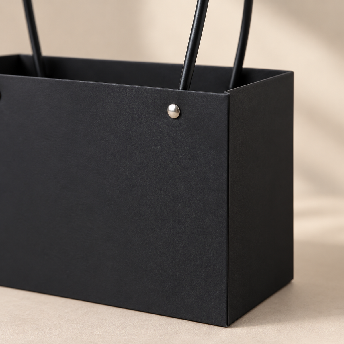 Close-up of the black cardstock floral tote corner, silver rivet and narrow loop handles.