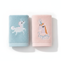 Pink and blue unicorn embroidered plush cotton towels folded on white background