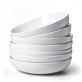 Set of six white porcelain ribbed pasta bowls stacked on white