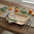 Natural pressed palm leaf disposable rectangular plate styled on a rustic wood table with linen napkin and greenery