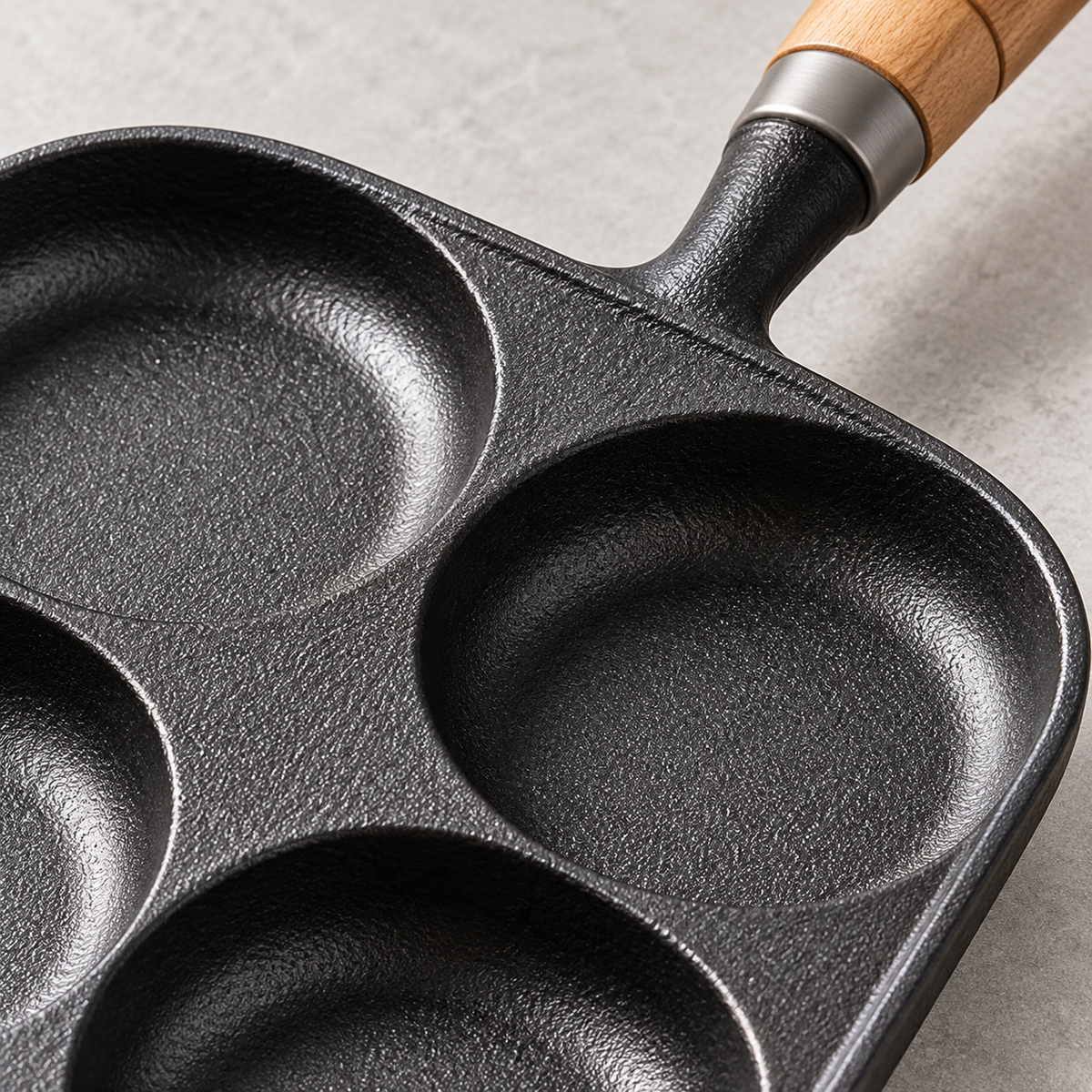 Close-up of the four-well frying pan cast iron surface and handle connection