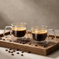 Pair of double-wall glass coffee cups with espresso on a wooden tray