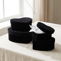 Four graduated black velvet heart gift boxes on cream linen with lid lifted
