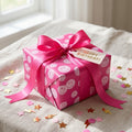 Birthday gift wrapped in pink preppy smiley paper with hot pink ribbon