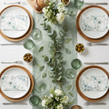 Fresh sage and eucalyptus garden brunch table setting with botanical print napkins, silver cutlery, and eucalyptus stems