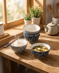 Five floral porcelain bowls displayed on a kitchen shelf with soup and rice
