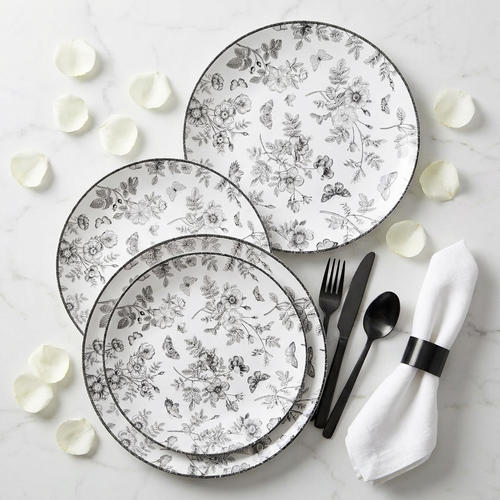 Black and white disposable plates fanned on marble with matte black cutlery and white rose petals