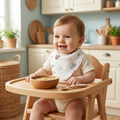 Adorable baby wearing cotton triangle bear bib in high chair at mealtime