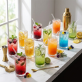 12 clear hobnail highball cocktail glasses with colorful drinks on marble bar