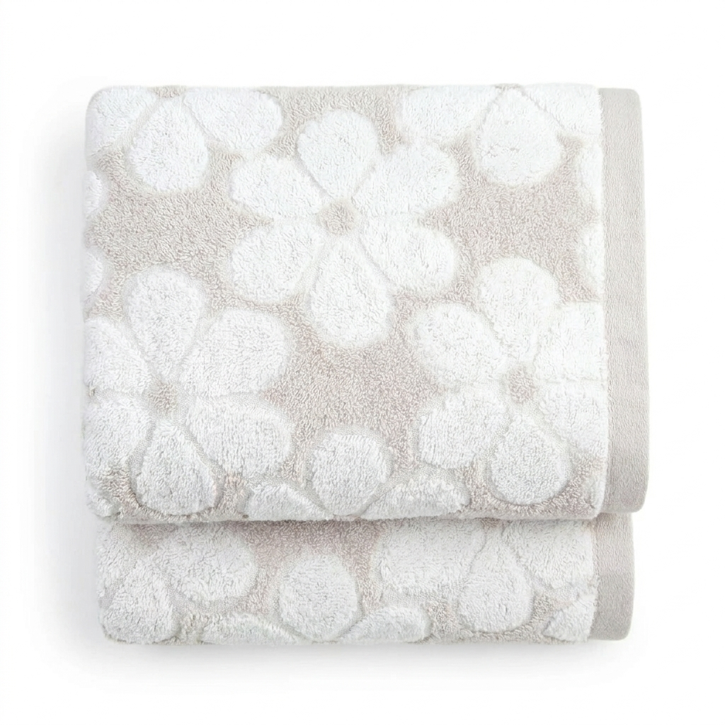 Two light beige floral jacquard bath towels neatly folded on white background
