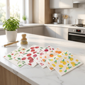 6 fruit-print Swedish dishcloths fanned on marble kitchen counter with herb plant and dish brush