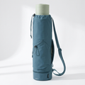 Blue cylindrical yoga mat carrier bag with rolled mat inside, pockets and drawstring closure visible
