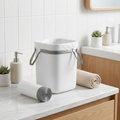 Small white drawstring trash bags lining a sleek bathroom bin on a marble countertop