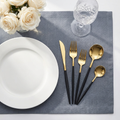 Gold and black handle 24-piece flatware set in an elegant formal dinner table place setting with white plate and crystal wine glass
