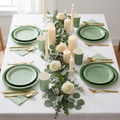 Sage green gradient party tableware in an elegant table setting with eucalyptus, ivory candles, gold cutlery, and white roses