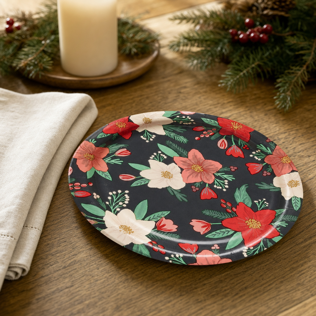 Christmas dessert place setting on a warm oak table with the black winter floral plate and a folded cream linen napkin